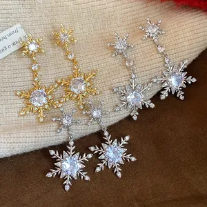 Detail of sparkling cubic zirconia snowflake earrings on soft knitted background.
