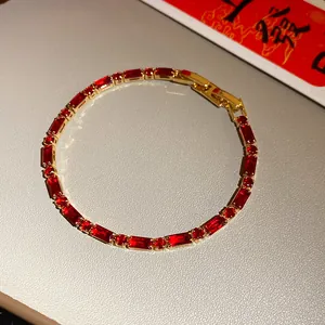 Close-up detail of elegant gold bracelet set with rectangular red zirconia stones