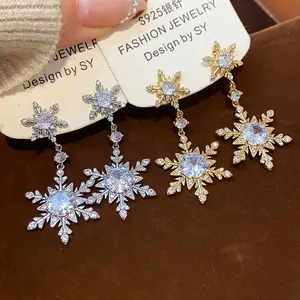 Close-up detail of gold and silver snowflake dangle earrings with sparkling zircons