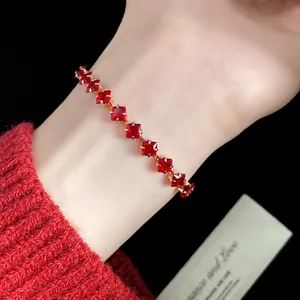 Close-up of elegant red square zircon bracelet worn on wrist with cozy red sleeve