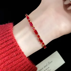 Detailed view of a vintage red zircon bracelet on a wrist with a matching red sweater.