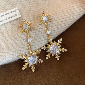 Detail of sparkling gold-plated snowflake dangling earrings with zircon stones