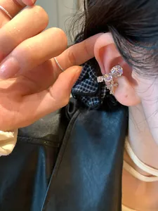 Detailed view of a silver-tone zircon ear cuff featuring a delicate cross charm pendant.