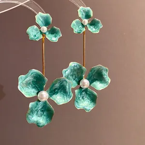 Nahaufnahme der teegrünen Emaille-Blumenohrringe mit weißen Perlenakzenten in Gold