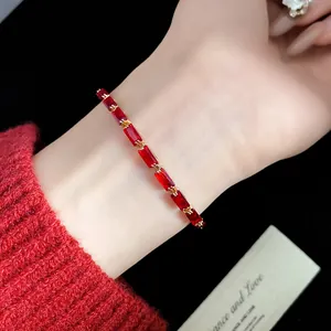 Close-up of elegant gold bracelet featuring rectangular red zircons on wrist