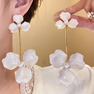 Detailansicht eleganter Blumen-Ohrhänger mit weißen Emaille-Blütenblättern und Perlen.