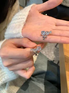 Detailed close-up of sparkling zirconia round cross ear clips held in hand for scale