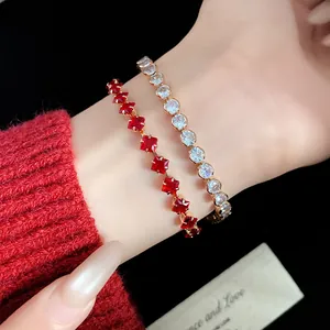 Close-up of vintage gold-toned zircon bracelets with red and clear stones on wrist.