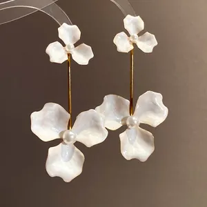 Elegante weiße Emaille-Blumen-Ohrhänger mit glänzenden Perlenmitten in Nahaufnahme