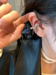 Macro view of silver-tone ear cuff featuring sparkling zirconia and cross pendant