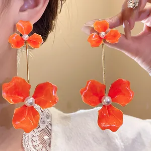 Detailansicht der übergroßen orangefarbenen Emaille-Blumen-Ohrhänger mit Perlenzentrum
