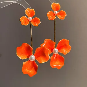Detailansicht der leuchtend orangefarbenen Emaille-Blumenohrringe mit weißen Perlen