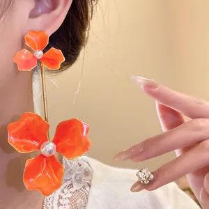 Detailansicht von orangefarbenen Blumenohrringen mit Perlen und Stahlnadeln für einen süßen Look
