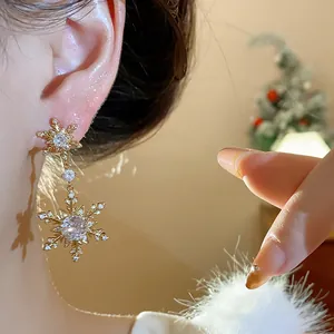 Close-up of a gold-plated snowflake earring with sparkling zircons on an ear.