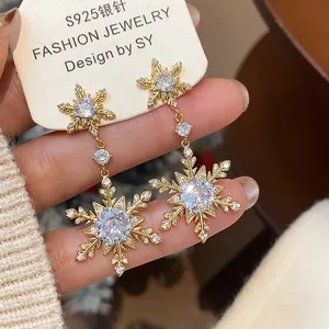 Macro view of gold plated snowflake earrings with shiny zircon stones for winter fashion