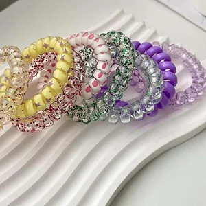 Close-up detail of colorful candy-colored spiral telephone cord hair ties set on white tray