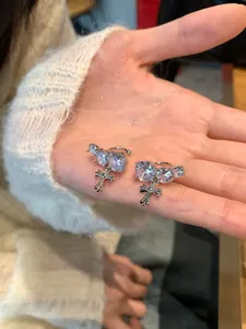 Detailed view of sparkling round zirconia cross ear cuffs held in palm for display