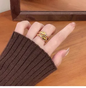 Detailed close-up view of vintage gold-plated rings with zircon and tiger eye stones on finger