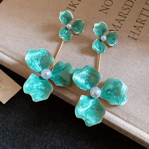Nahaufnahme von minzgrünen Emaille-Blumenohrringen mit zentralen weißen Perlen