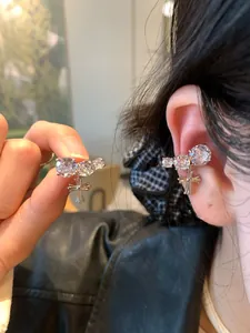 Detailed view of silver cross ear cuff with sparkling zircons worn on ear bone.