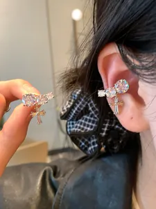 Detailed shot of sparkling cubic zirconia ear cuffs with hanging cross charms worn on the ear