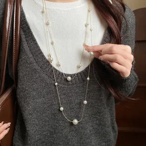 Detailed view of a double-layered vintage pearl necklace worn on a soft grey sweater