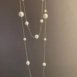Detail of a double-layered gold chain necklace featuring assorted elegant white pearls