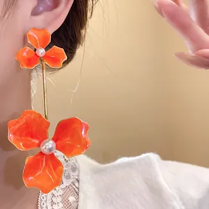 Detailansicht von leuchtend orangefarbenen Emaille-Ohrhängern mit Perlenakzenten