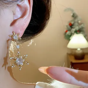 Detailed view of gold-plated snowflake earrings with sparkling zircons on ear