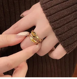 Close-up detail of vintage gold-plated rings with tiger's eye and zircon stones on hand