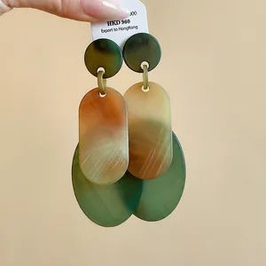 Elegant oval acrylic dangle earrings with marbled green and amber patterns.