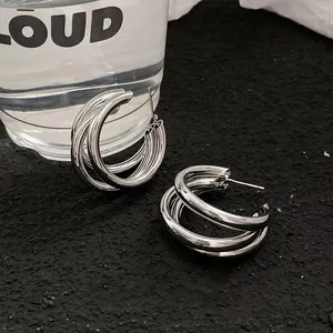 Close-up of silver triple-layered metal hoop earrings with a minimalist cool style