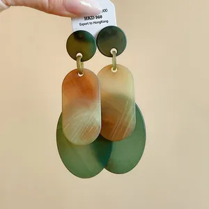 Close-up of retro green and amber marble oval acrylic drop earrings with silver needles
