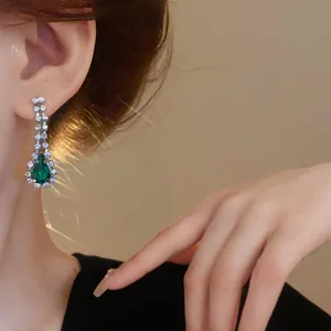 Primo piano di orecchini a goccia verde smeraldo in stile francese indossati dalla modella