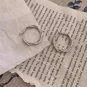 Detailed view of silver twisted double hoop earrings on aesthetic paper background