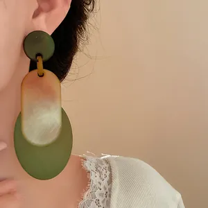 Close-up of vintage-style oval acrylic drop earrings with green and marble textures