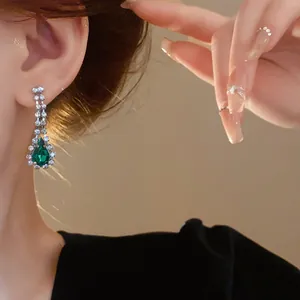 Dettaglio elegante di orecchini a goccia francesi di lusso con strass verdi indossati sull'orecchio