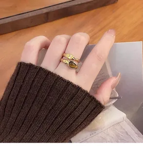 Close-up view of gold-plated rings with zircon and faux tiger eye stone on finger