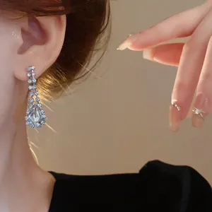 Primo piano di orecchini pendenti con strass a goccia su una modella asiatica, dettagli fini.
