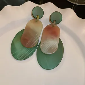 Detailed macro view of retro green and marble textured acrylic oval earrings on plate
