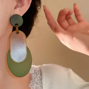 Close-up view of vintage-style layered acrylic oval earrings worn by a model