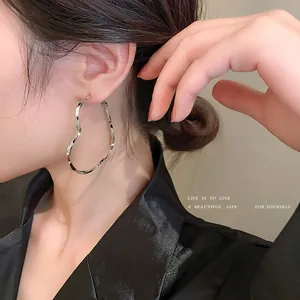 Close-up detail of a stylish silver heart-shaped hoop earring worn by a female model