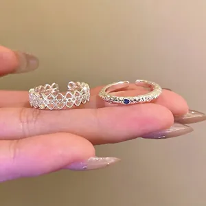 Detailansicht der silbernen offenen Ringe mit Blumenmuster und kleinem blauen Stein