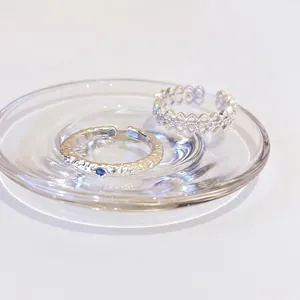 Elegante silberne hohlgearbeitete Blumen- und Strukturringe auf Glasteller