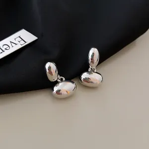 Close-up view of silver pebble-shaped earrings with a glossy metallic finish and minimalist design