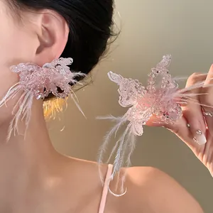 Detailansicht eines rosa Kristall-Schmetterlings-Schmucks mit feinen weißen Federn