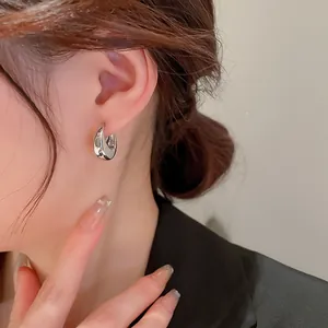 Detailed close-up view of minimalist silver metallic hoop earrings worn by an elegant model