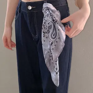 Elegant paisley print silk-like scarf styled as a chic decorative waist accessory on denim.