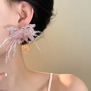 Detailansicht eleganter rosa Feder- und Kristall-Schmetterlingsohrringe an einem Model