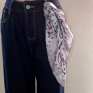 Elegant paisley pattern silk-feel headscarf tied on jeans as a stylish fashion accessory